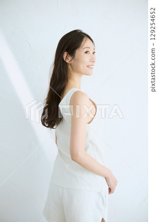 Smiling young woman touching her skin and doing skin care - 129254652