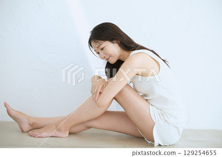 微笑的年輕女子觸摸她的皮膚並進行皮膚護理 - 129254655