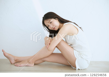 Smiling young woman touching her skin and doing skin care - 129254656
