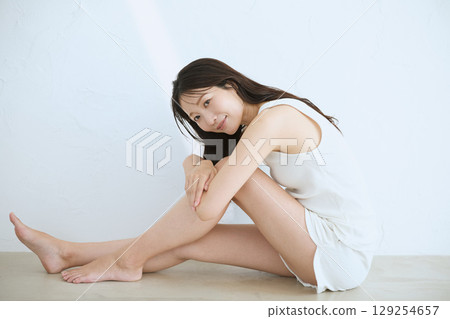 微笑的年輕女子觸摸她的皮膚並進行皮膚護理 - 129254657