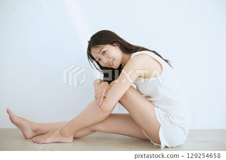 微笑的年輕女子觸摸她的皮膚並進行皮膚護理 - 129254658