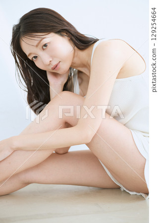 微笑的年輕女子觸摸她的皮膚並進行皮膚護理 - 129254664