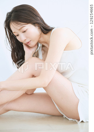 微笑的年輕女子觸摸她的皮膚並進行皮膚護理 - 129254665