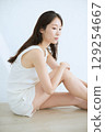 微笑的年輕女子觸摸她的皮膚並進行皮膚護理 - 129254667