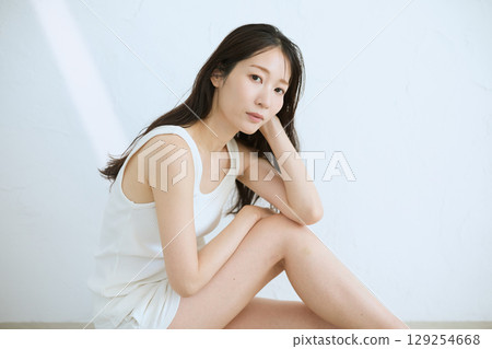 Smiling young woman touching her skin and doing skin care - 129254668