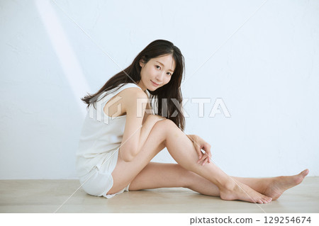 Smiling young woman touching her skin and doing skin care - Smiling young woman touching her skin and doing skin care - 129254674