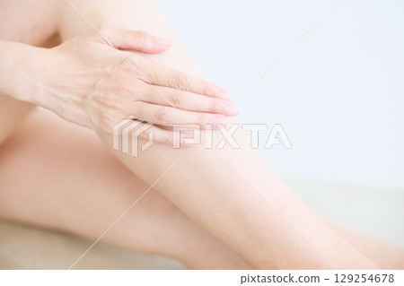 Smiling young woman touching her skin and doing skin care - Smiling young woman touching her skin and doing skin care - 129254678