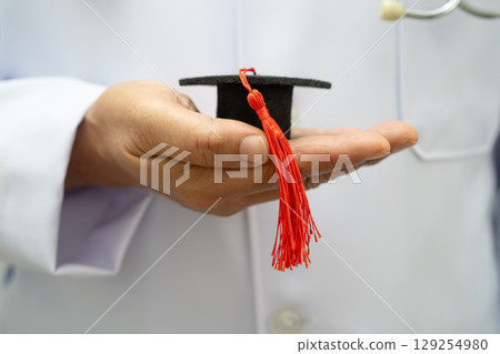 Asian woman doctor holding graduation hat in hospital, Medical education. 129254980