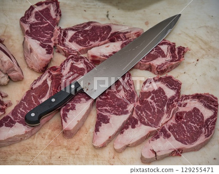 Rustic food photography showing traditional meal preparation with fresh raw beef, pork, and ingredients on butcher's table. 129255471