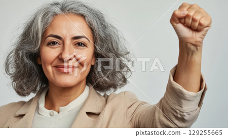 Middle aged latin american woman with raised fist symbolizing empowerment, strength and women solidarity, International Womens Day concept 129255665