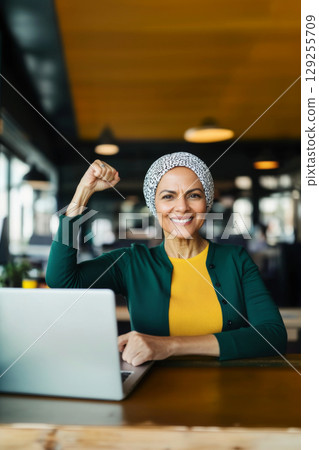 Muslim middle eastern woman in office with raised fist of empowerment, strength and women solidarity, International Womens Day concept 129255709