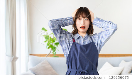 一個穿著圍裙的女人抱著頭擔心 一個穿著圍裙的女人抱著頭擔心 129256075