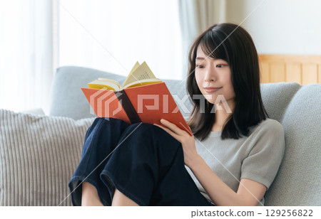 A woman sitting on a sofa and reading A woman sitting on a sofa and reading 129256822