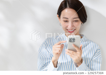 Woman operating a smartphone Woman operating a smartphone 129257384