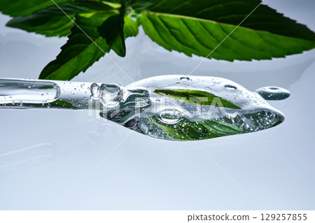 A pipette with a drop of serum in refreshing mint leaves. A pipette with a drop of serum in refreshing mint leaves. 129257855