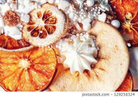 Easter cake decor. Cooked fruitcake decorated dry oranges slices, pears, white meringue, candies sprinkled, top view 129258324