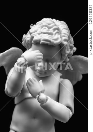 Sad cherub with facepalm gesturing. Angel figurine holding his head in hands 129258325