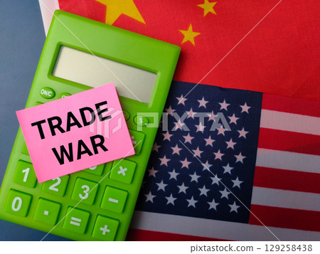 Top view calculator and sticky note with the word TRADE WAR on a us america and china flag background.Geopolitical Concept. 129258438