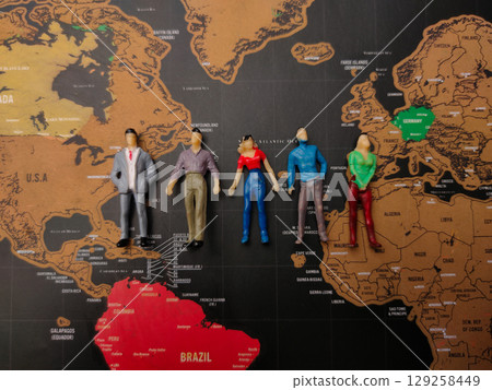 Top view men and women miniature people stand on a world map background. Geopolitics concept. Top view men and women miniature people stand on a world map background. Geopolitics concept. 129258449