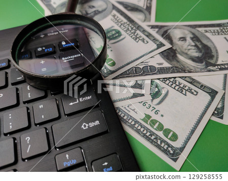Closeup magnifying glasd,banknote and keyboard business online concept. Closeup magnifying glasd,banknote and keyboard business online concept. 129258555