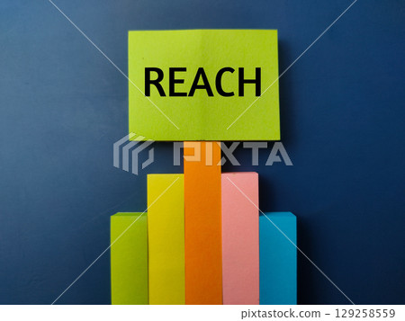 Graf sticky note with the word REACH on a blue background. 129258559