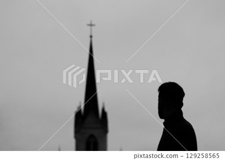 A powerful silhouette of a man near church. This image evokes strong themes of religion, praise, and faith in Jesus and Christ, with a subtle hint of a church setting 129258565