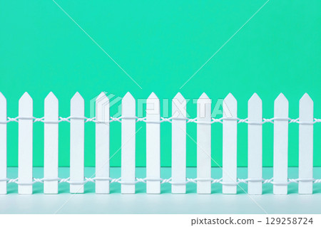 Wooden toy white picket fence on green background. Small painted simple wood decorative fencing 129258724