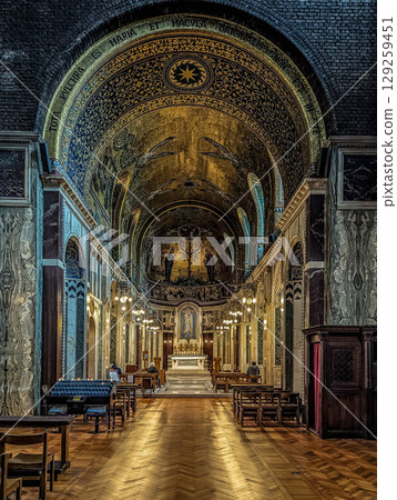 Interior view of Westminster Cathedral with illuminated columns and arched ceiling during evening service. Interior view of Westminster Cathedral with illuminated columns and arched ceiling during evening service. 129259451