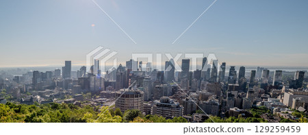 Scenic view of Montreal's skyline showcasing its diverse architecture, with lush green trees in the foreground and the St. Lawrence River in background. Scenic view of Montreal's skyline showcasing its diverse architecture, with lush green trees in the foreground and the St. Lawrence River in background. 129259459
