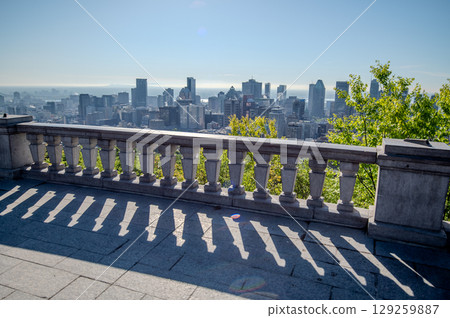 Scenic view of Montreal's skyline showcasing its diverse architecture, with lush green trees in the foreground and the St. Lawrence River in background. 129259887
