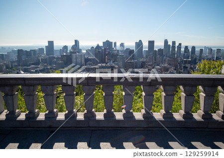 Scenic view of Montreal's skyline showcasing its diverse architecture, with lush green trees in the foreground and the St. Lawrence River in background. Scenic view of Montreal's skyline showcasing its diverse architecture, with lush green trees in the foreground and the St. Lawrence River in background. 129259914