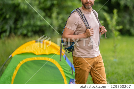 Man on summer camping. Camp adventure. Hiking concept. Camping tent. Man on camp in forest with tent, cropped view. Man hiker outdoor on summer day. Summer camp and nature vacation Man on summer camping. Camp adventure. Hiking concept. Camping tent. Man on camp in forest with tent, cropped view. Man hiker outdoor on summer day. Summer camp and nature vacation 129260207