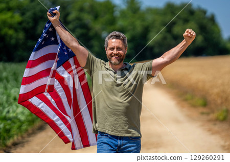 Labor day. American flag and man farmer, harvest. Flag of USA. Independence day. Man in field. Patriotic man with American flag in field. Independence day of America. 4th of July celebration Labor day. American flag and man farmer, harvest. Flag of USA. Independence day. Man in field. Patriotic man with American flag in field. Independence day of America. 4th of July celebration 129260291