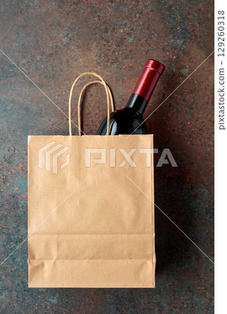 Bottle of red wine in a paper bag on a rusty background. Bottle of red wine in a paper bag on a rusty background. 129260318
