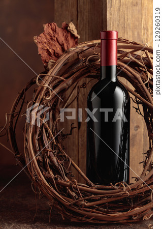 Bottle of red wine and dried grapevine wreath. Bottle of red wine and dried grapevine wreath. 129260319