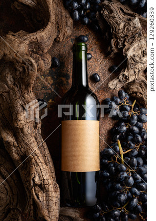 Bottle of red wine with blue grapes and old weathered snags. Bottle of red wine with blue grapes and old weathered snags. 129260339