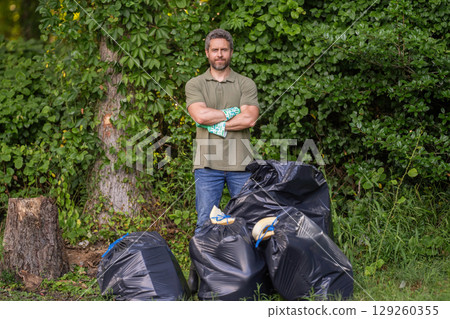 Save environment. Environment plastic pollution. Volunteer man collecting garbage in forest. Environmental protection. Man environmental activist. Environmental conservation. Recycling 129260355