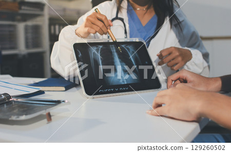 Cropped shot of an unrecognisable doctor sitting with his patient and showing her x-rays on a digital tablet 129260502