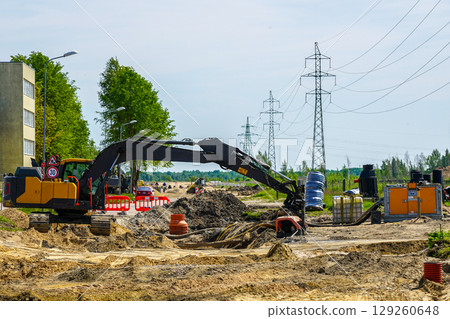 Excavator and Dewatering Pump at Urban Construction Site with Power Lines and Pipe Installation Excavator and Dewatering Pump at Urban Construction Site with Power Lines and Pipe Installation 129260648