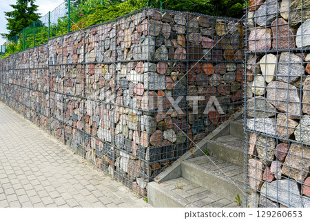 Modern Gabion Retaining Wall with Stone Fill and Concrete Staircase in Urban Landscape Design 129260653