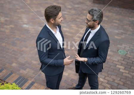 Business negotiation success. Business partner outdoor. Two businessmen in suit. Business conversation. Project partner talking. Successful businessmen. Successful partnership communication 129260769