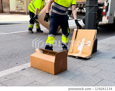 City street cardboard cleanup by workers in safety gear 129261134