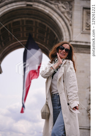 Woman in trench coat with French flag in Paris Woman in trench coat with French flag in Paris 129261221