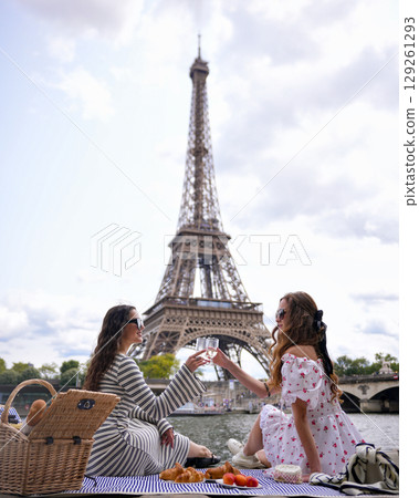 Women clinking glasses during picnic near Eiffel Tower  129261293