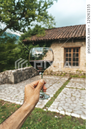 Red Wine Glass in Hand with Stone Cellar Background in France or Italy Red Wine Glass in Hand with Stone Cellar Background in France or Italy 129261535
