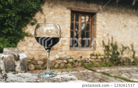 Glass of Red Wine in Front of Stone Wine Cellar in France or Italy 129261537