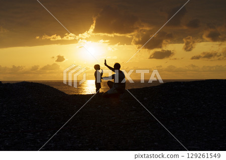 Father and Son Silhouettes at Sunset. Family Bonding Moment 129261549