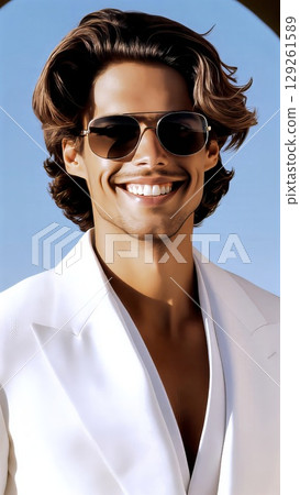 Confident male model sporting long brown hair, white suit, sunglasses, standing against bright blue sky background 129261589