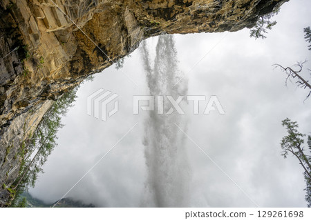 Water cascades powerfully down from Johannes Waterfall, surrounded by rugged cliffs and lush greenery. The mist rising creates a mesmerizing atmosphere, drawing visitors to admire its beauty. 129261698