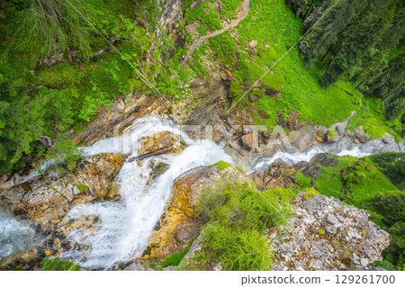 Johannes Waterfall cascades down rocky terrain surrounded by lush greenery in Obertauern. Visitors can enjoy the serene beauty of the Alps and hear the tranquil sounds of rushing water. 129261700
